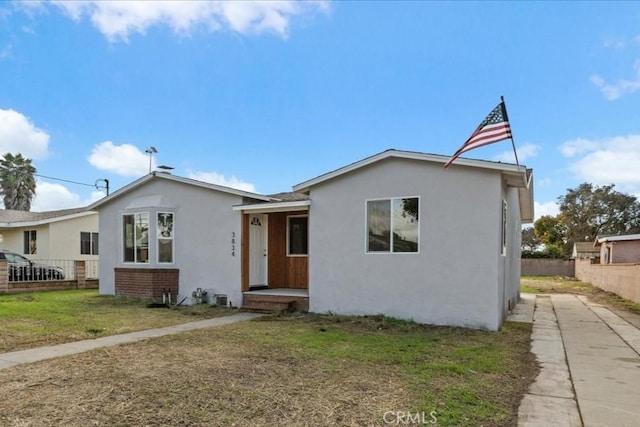 view of front of property featuring brick siding, fence, and stucco siding