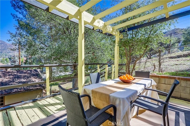 deck featuring outdoor dining space, a mountain view, and a pergola