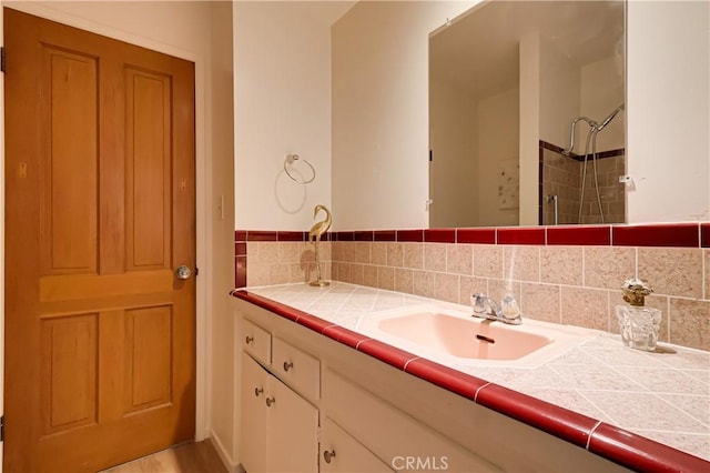 bathroom featuring tiled shower, vanity, and decorative backsplash