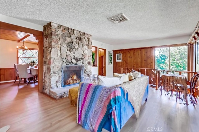 living room with wood walls, wood finished floors, visible vents, and plenty of natural light