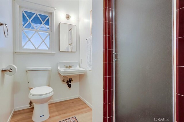 full bathroom featuring toilet, a shower stall, wood finished floors, and baseboards