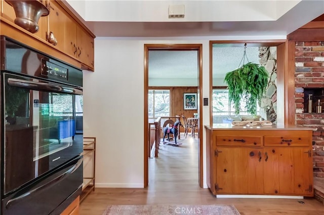 kitchen featuring light wood-type flooring, dobule oven black, light countertops, and baseboards