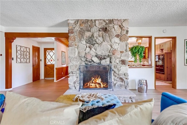 living room featuring a textured ceiling, a fireplace, and wood finished floors