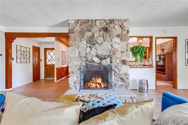 living area featuring a fireplace, a textured ceiling, and wood finished floors
