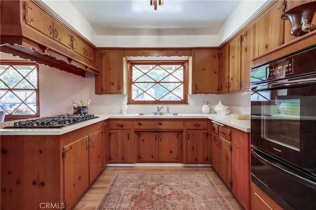 kitchen featuring a warming drawer, brown cabinets, light countertops, and gas cooktop