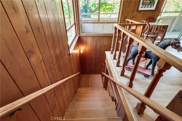 stairway featuring wood finished floors and wooden walls