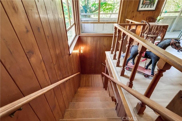 staircase featuring wooden walls and wood finished floors