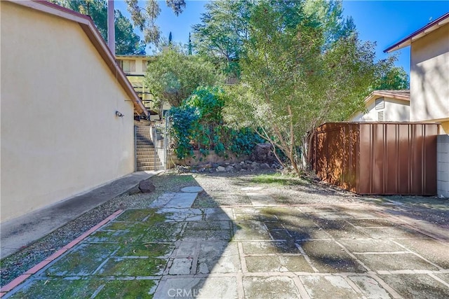 view of patio featuring stairs and fence