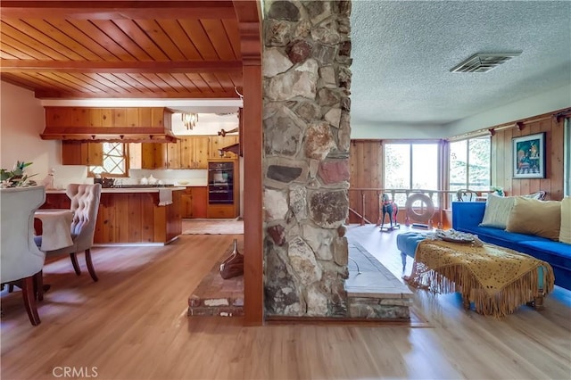 living room featuring light wood finished floors, visible vents, and a textured ceiling