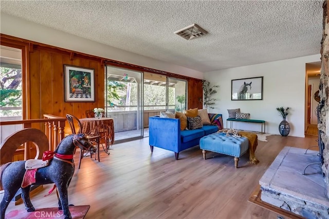 living room featuring a textured ceiling, visible vents, and light wood-style floors