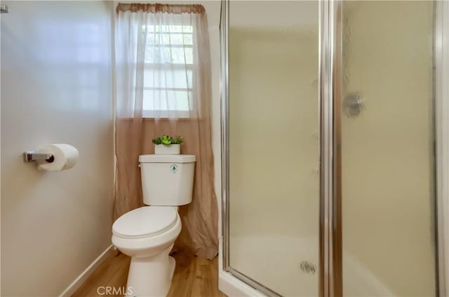 full bath featuring a stall shower, wood finished floors, toilet, and baseboards