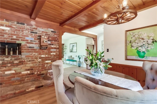 dining area featuring brick wall, wood ceiling, beamed ceiling, wood finished floors, and a chandelier