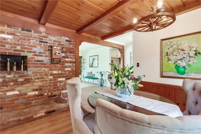 dining space with wooden ceiling, a notable chandelier, brick wall, beam ceiling, and wood finished floors