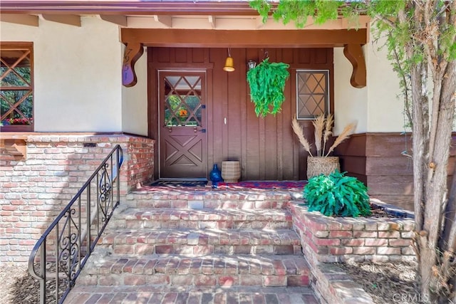 view of exterior entry featuring brick siding and stucco siding