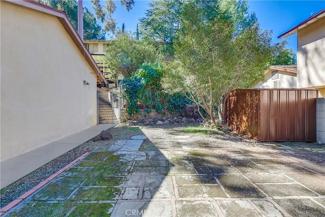 view of yard with a patio, fence, and stairs