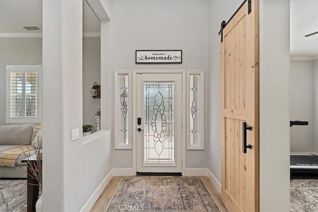 entrance foyer with baseboards, ornamental molding, and wood finished floors