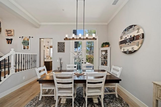 dining area with a notable chandelier, visible vents, baseboards, light wood-type flooring, and crown molding