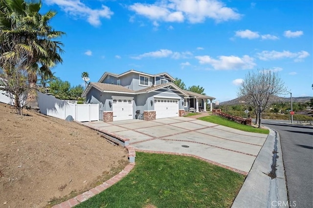 craftsman inspired home with an attached garage, fence, concrete driveway, and stucco siding