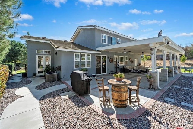 rear view of property featuring french doors, stucco siding, outdoor lounge area, a ceiling fan, and a patio area