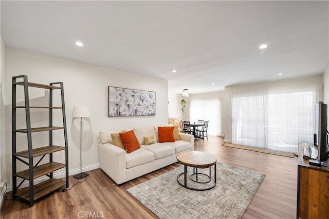 living area with baseboards, wood finished floors, and recessed lighting