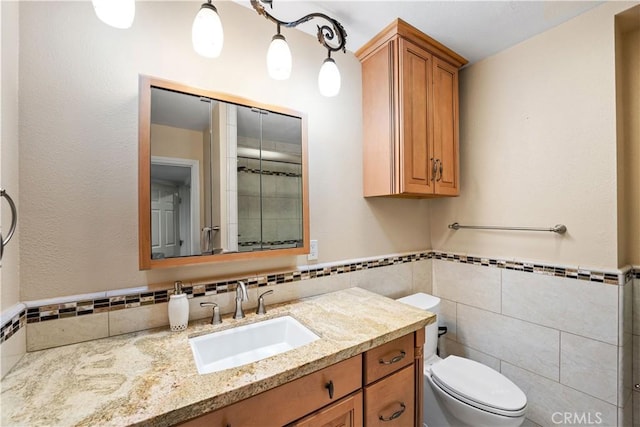 bathroom with vanity, toilet, and tile walls