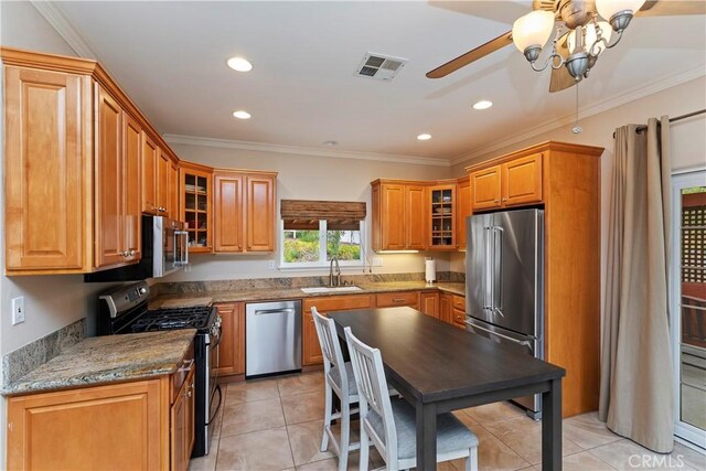 kitchen featuring visible vents, a sink, appliances with stainless steel finishes, crown molding, and brown cabinets