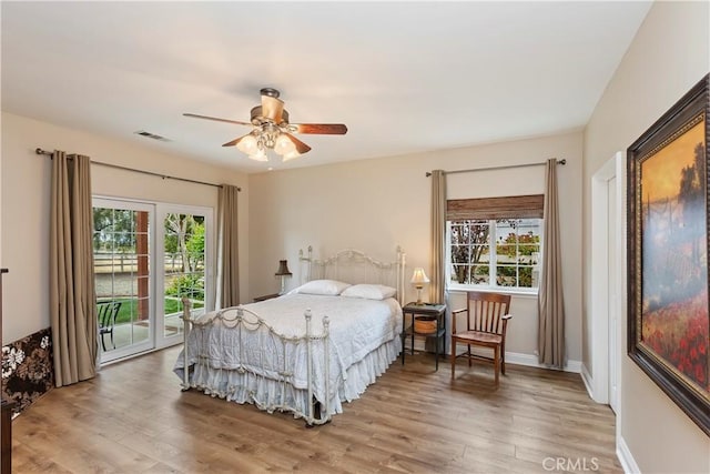 bedroom with access to outside, wood finished floors, visible vents, and baseboards