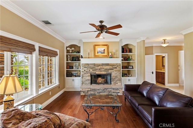 living area with a stone fireplace, built in features, wood finished floors, and visible vents