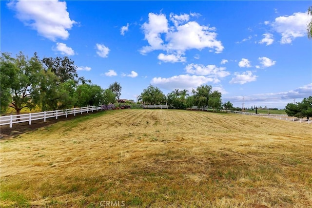 view of yard featuring an enclosed area, a rural view, and fence