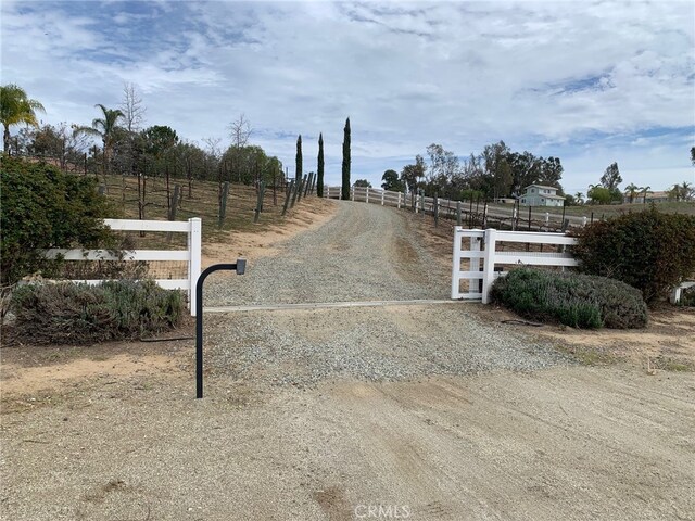 view of road with a gate, a rural view, driveway, and a gated entry