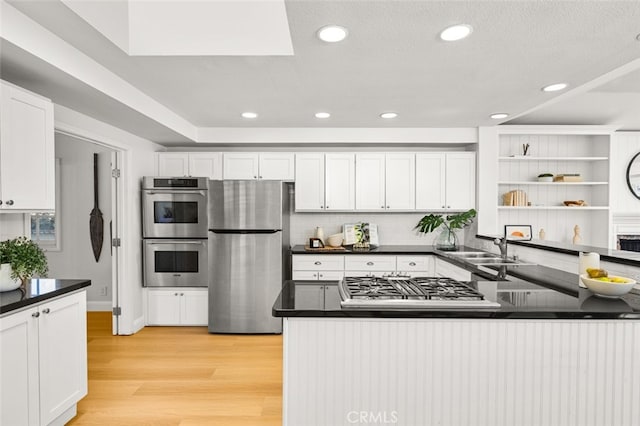 2851 Catalpa St, Newport Beach, CA 92660 - kitchen featuring stainless steel appliances, a sink, white cabinetry, light wood-style floors, and dark countertops