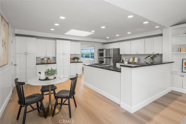 2851 Catalpa St, Newport Beach, CA 92660 - kitchen featuring dark countertops, a skylight, appliances with stainless steel finishes, and light wood finished floors
