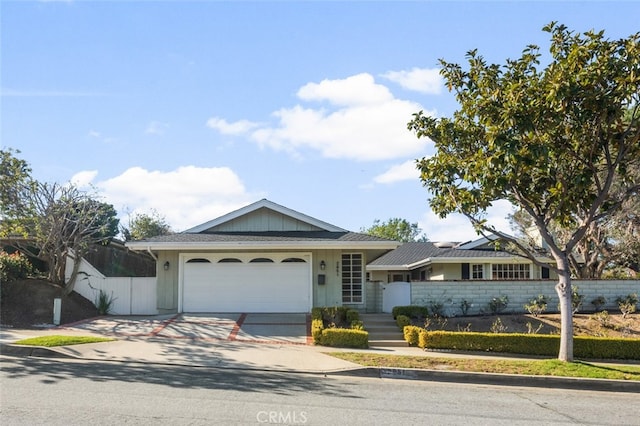 ranch-style house featuring a garage, driveway, and fence