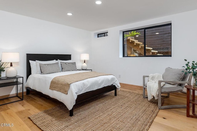 bedroom featuring baseboards, light wood finished floors, and recessed lighting