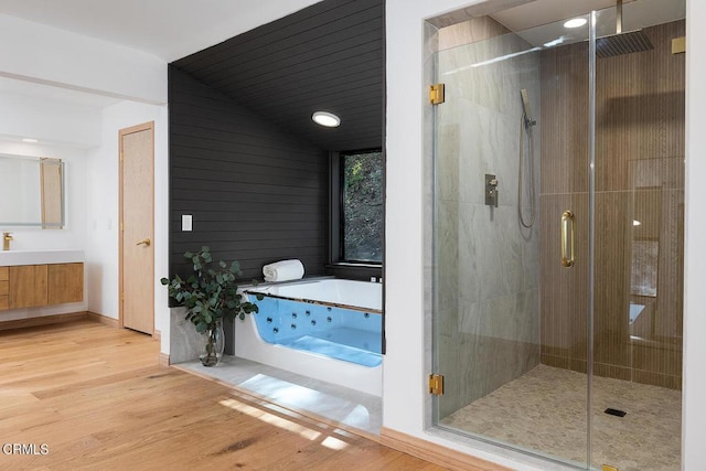 full bath with a stall shower, wood finished floors, vanity, and a jetted tub