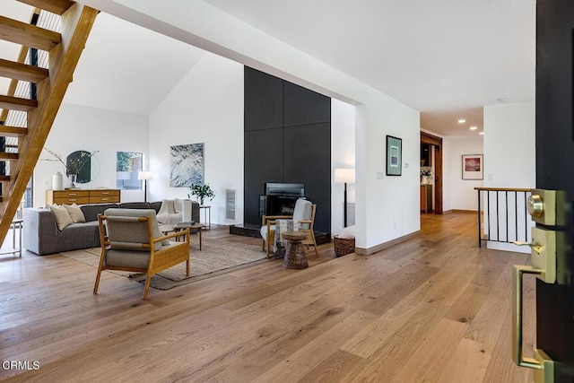 living area featuring baseboards, visible vents, a towering ceiling, stairs, and light wood-style floors