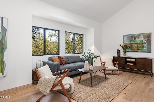 sitting room with vaulted ceiling, light wood-type flooring, and baseboards