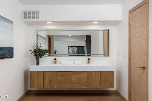 bathroom featuring visible vents, a sink, baseboards, and double vanity