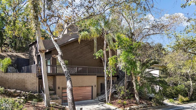 view of front of home featuring an attached garage, driveway, stairs, and stucco siding