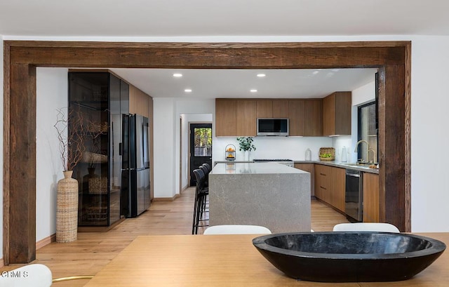 kitchen with stainless steel appliances, light wood-style floors, a kitchen island, a sink, and modern cabinets