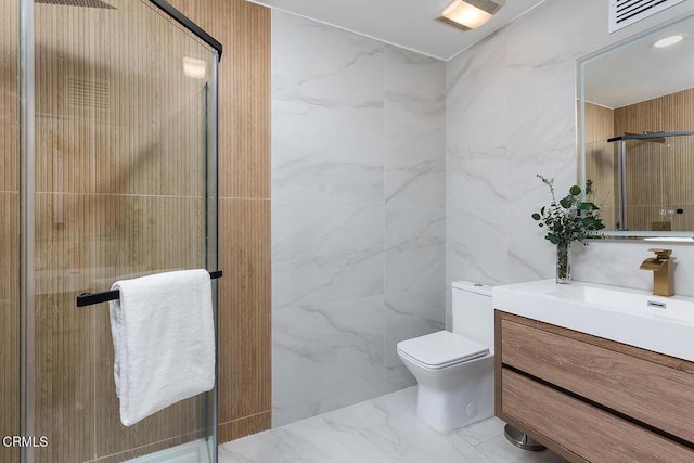 bathroom featuring marble finish floor, tile walls, toilet, a shower stall, and vanity