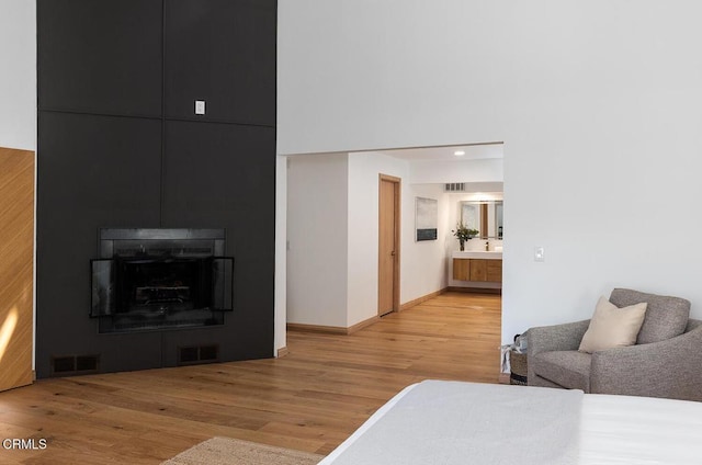 bedroom with a large fireplace, visible vents, and light wood-style flooring