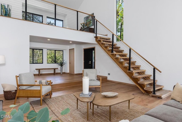 living room with baseboards, a towering ceiling, stairway, wood finished floors, and recessed lighting