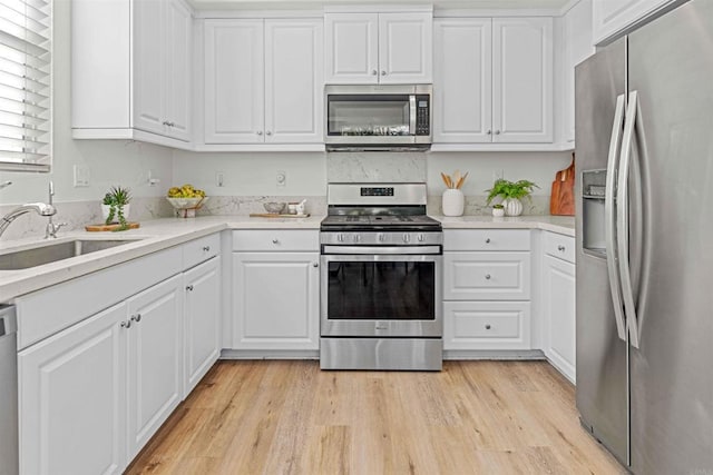 kitchen featuring stainless steel appliances, light wood finished floors, light countertops, and white cabinetry