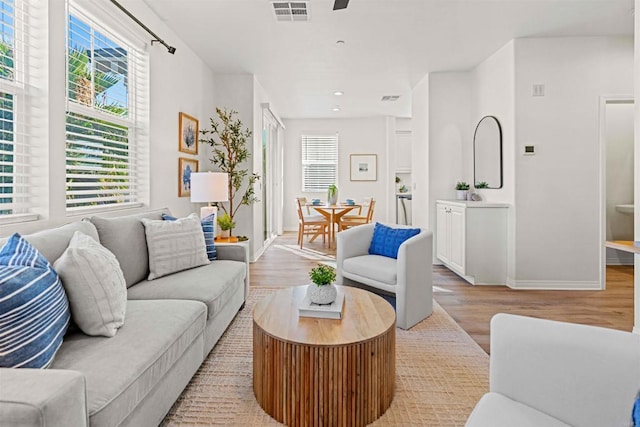 living area with a healthy amount of sunlight, light wood finished floors, and visible vents