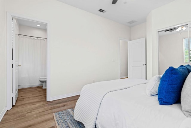 bedroom with ceiling fan, ensuite bathroom, wood finished floors, visible vents, and baseboards