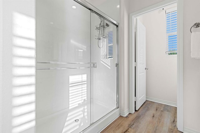 bathroom featuring a shower stall, baseboards, and wood finished floors