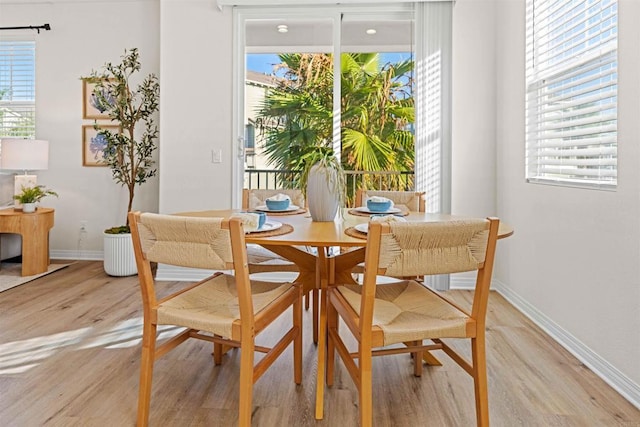 dining space with light wood-type flooring, a wealth of natural light, and baseboards