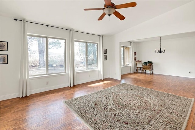 interior space with vaulted ceiling, ceiling fan with notable chandelier, wood finished floors, and baseboards