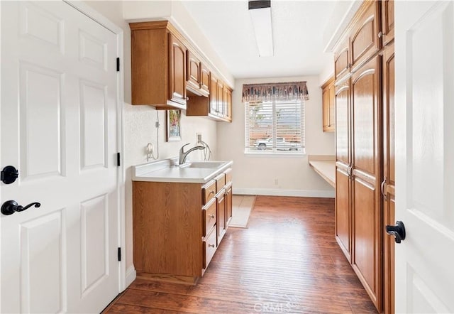 kitchen with brown cabinets, light countertops, a sink, and wood finished floors